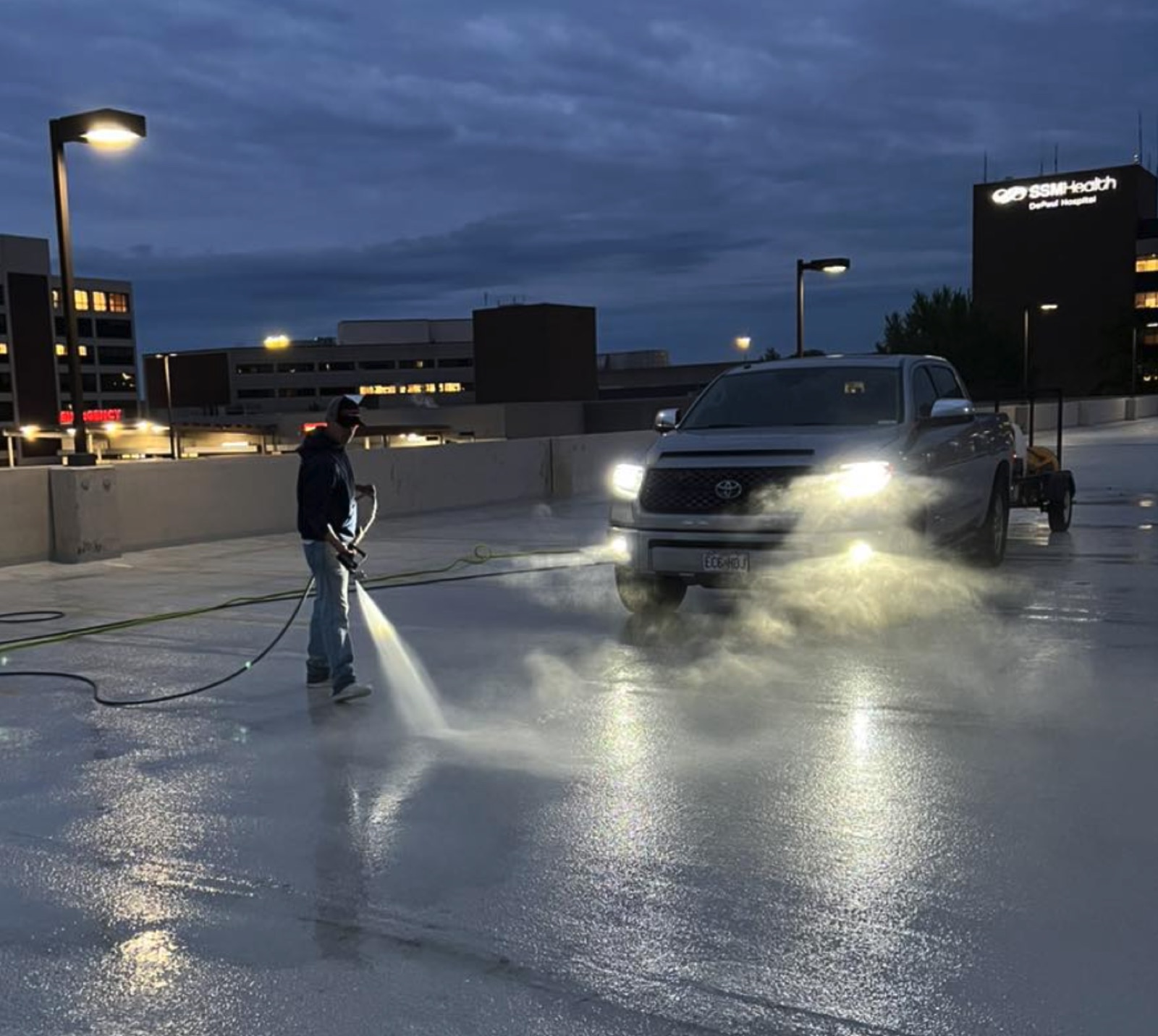 ATC pressure washing a parking garage deck at dusk